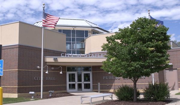 Staples library with two flags and a tree in front