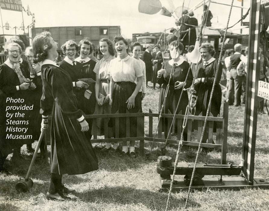 Group of women laughing around a hammer game at a fair