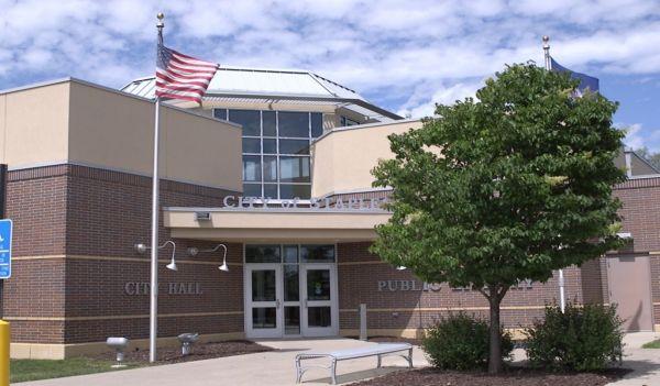 Staples library with two flags and a tree in front